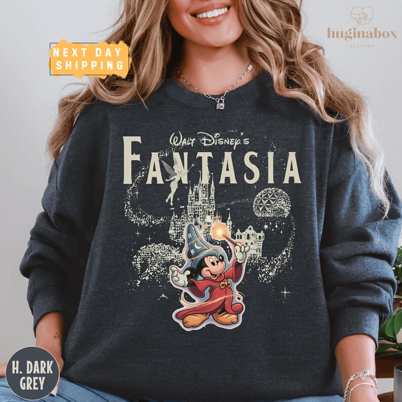A woman wearing a gray sweatshirt with a Disney-themed graphic of Mickey Mouse and a castle.