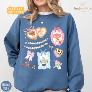 A woman wearing a blue sweatshirt with various cartoon-style illustrations and text on it.