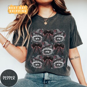 a woman wearing a shirt with raccoons on it