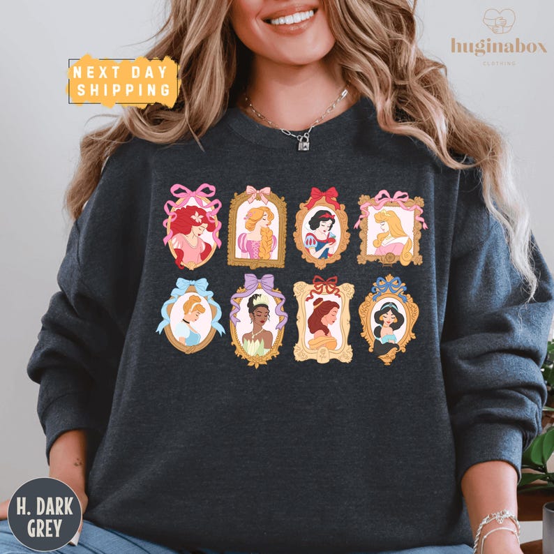 A woman wearing a gray sweatshirt with a graphic design of various Disney princesses in frames.