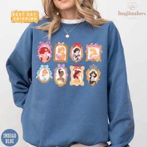 A woman wearing a blue sweatshirt with a collage of illustrations of Disney princesses on it.