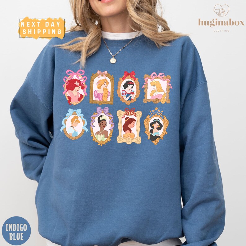 A woman wearing a blue sweatshirt with a collage of illustrations of Disney princesses on it.