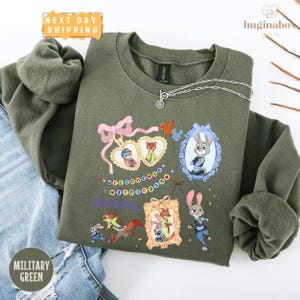 A military green sweatshirt with a colorful graphic design featuring cartoon characters and text.