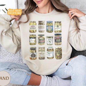 a woman sitting on a couch holding a jar of pickles