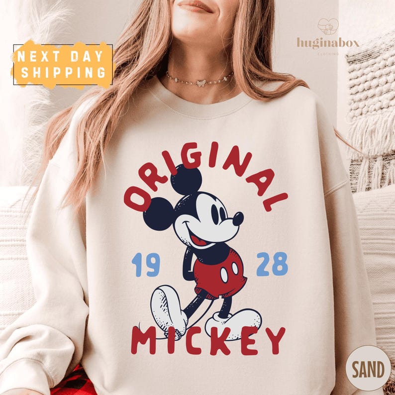 A woman wearing a white sweatshirt with a graphic of Mickey Mouse and the text "ORIGINAL MICKEY" printed on it.