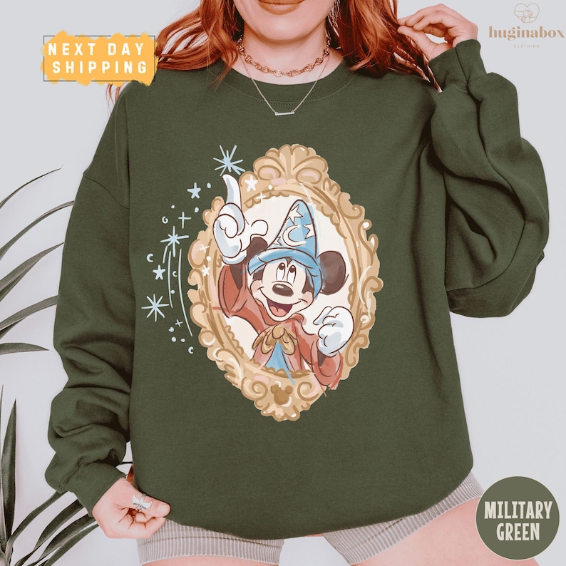 A person wearing a green sweatshirt with a Mickey Mouse design and a framed illustration of a wizard.