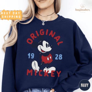 A woman wearing a navy blue sweatshirt with a graphic of Mickey Mouse printed on it.