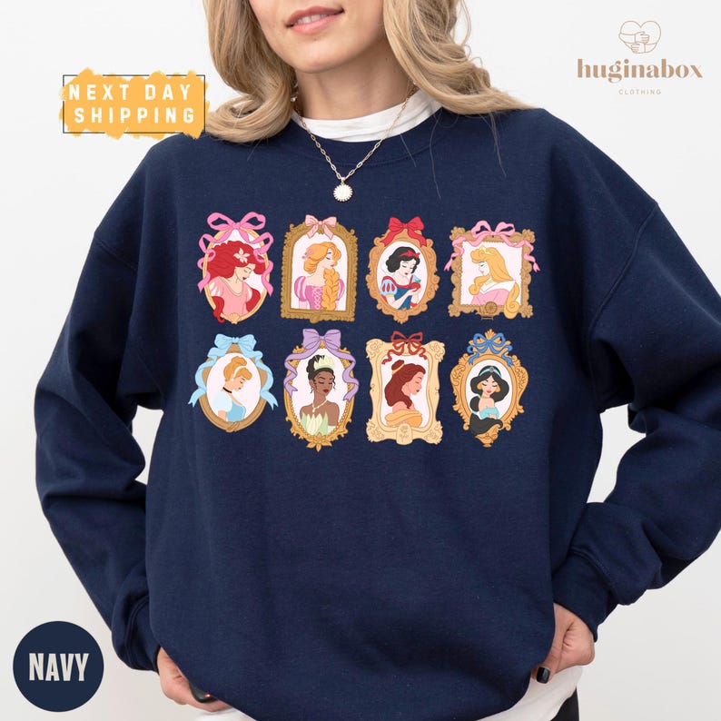 A woman wearing a navy blue sweatshirt with a collage of illustrations of Disney princesses on it.