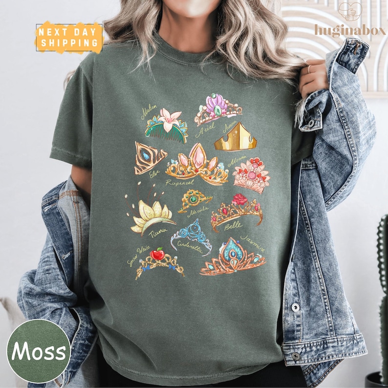 A person wearing a green t-shirt with a graphic design of various crowns and jewelry pieces.