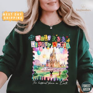 A woman wearing a green sweatshirt with a colorful graphic of Walt Disney World and the text "The happiest place on Earth".