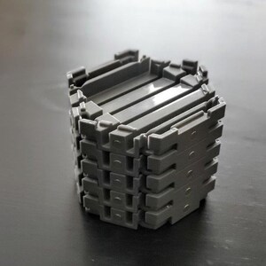 May include: A stack of gray plastic building blocks, forming a hexagonal shape.
