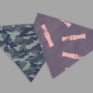 May include: Reversible dog or cat bandana with a camouflage pattern on one side and a pink duck call pattern on the other side.  Duck Calls & Camo Reversible Dog + Cat Bandana.