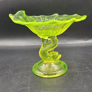 Compota de cristal vintage con base de delfín de uranio y diseño ondulado que brilla en la oscuridad.