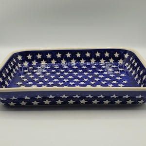 Op de afbeelding: Rechthoekige keramische ovenschaal met een blauwe achtergrond en een wit sterrenpatroon. De schaal heeft een cr&egrave;mekleurige rand en is ontworpen om in te bakken en te serveren. Het sterrenpatroon voegt een decoratief tintje toe.