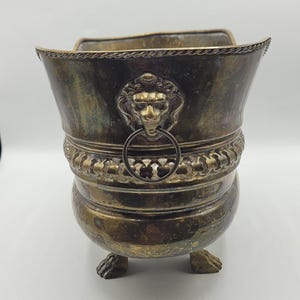 Vaso/Cachepot vintage em latão laqueado com cabeça de leão, formato retangular, pés em garra, alça dupla, detalhes trançados e recortes.