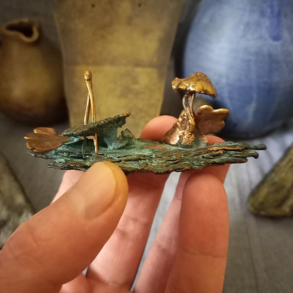 A figurine of natural mushrooms, leaves, bark and pine needles coated with copper using electroforming