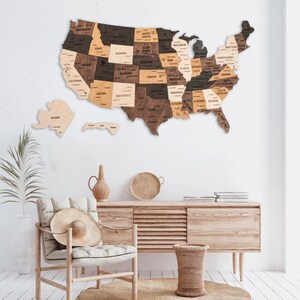 May include: A wooden map of the United States with each state outlined in a different shade of brown. The states are labeled with their names and major cities are marked with dots.