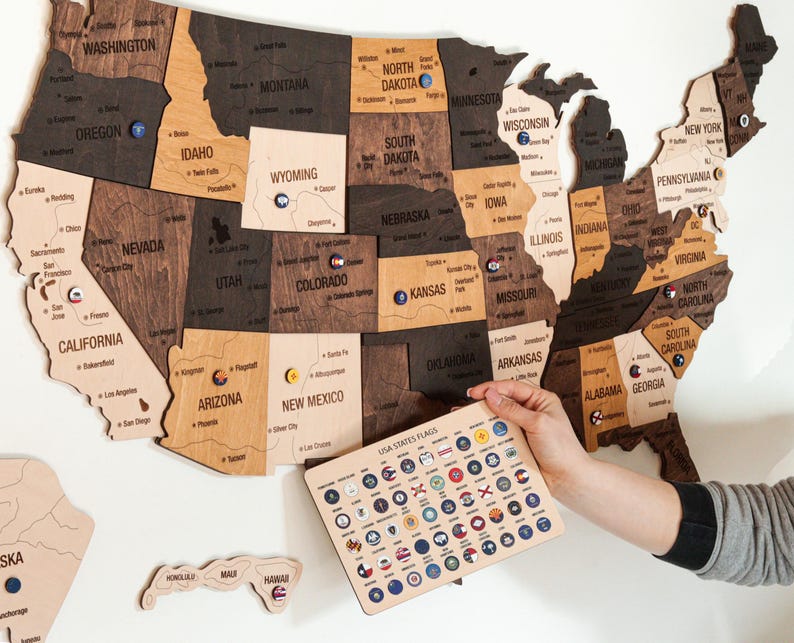 May include: A wooden map of the United States with each state outlined and labeled. The map is decorated with small, colorful flags representing each state. The flags are arranged in a grid on a separate wooden board labeled "USA States Flags".