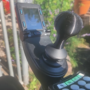 May include: A black joystick with a round, black knob and a small screen with the word "OFF" on it. The joystick is mounted on a black base with a series of buttons labeled with numbers.