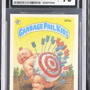 May include: A Garbage Pail Kids trading card featuring a baby with a target on its back and arrows sticking out of it. The card is yellow with blue and red accents. The card number is 255a and the title is "On The Mark".