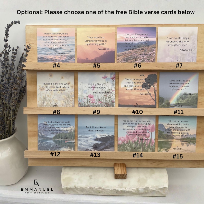 Peut inclure: Un pr&eacute;sentoir en bois clair contient douze cartes carr&eacute;es avec des versets bibliques, num&eacute;rot&eacute;es de 4 &agrave; 15. Chaque carte pr&eacute;sente un fond naturel unique, incluant des paysages, des fleurs et de l'eau, avec du texte et le logo Amy Designs.