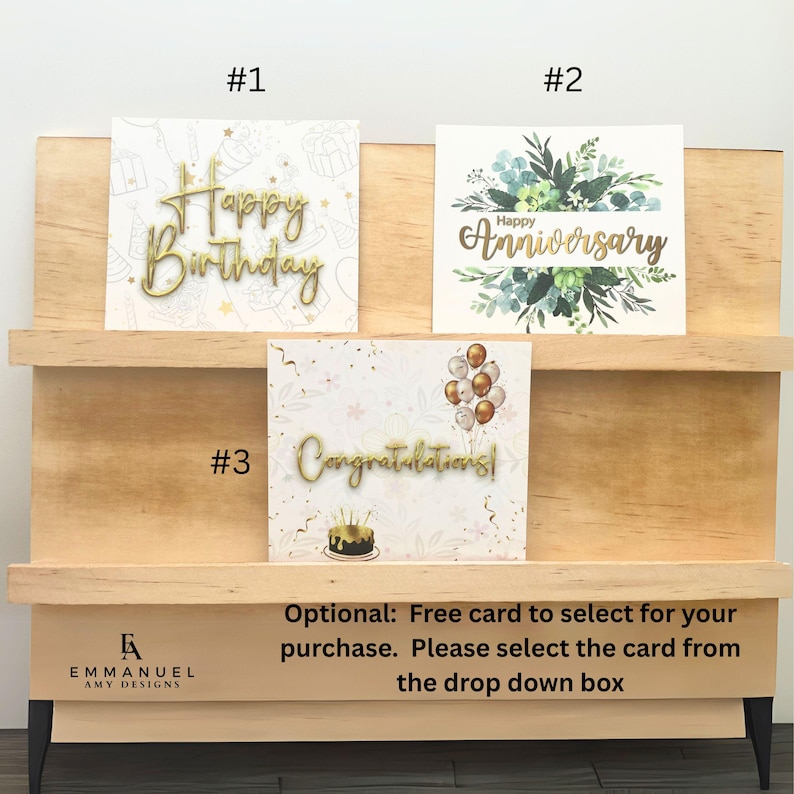 Peut inclure: Trois cartes de v&oelig;ux rectangulaires &eacute;tiquet&eacute;es #1, #2 et #3. La carte #1 pr&eacute;sente un texte dor&eacute; Happy Birthday. La carte #2 affiche un feuillage vert avec un texte dor&eacute; Happy Anniversary. La carte #3 montre des ballons et un g&acirc;teau avec un texte dor&eacute; Congratulations.