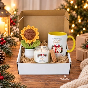 May include: A gift box containing a crocheted sunflower in a white pot, a white candle with a label reading A LIGHT OF HOPE THIS CHRISTMAS, and a white mug with a yellow handle featuring a gift graphic and THE GREATEST GIFT OF ALL text.