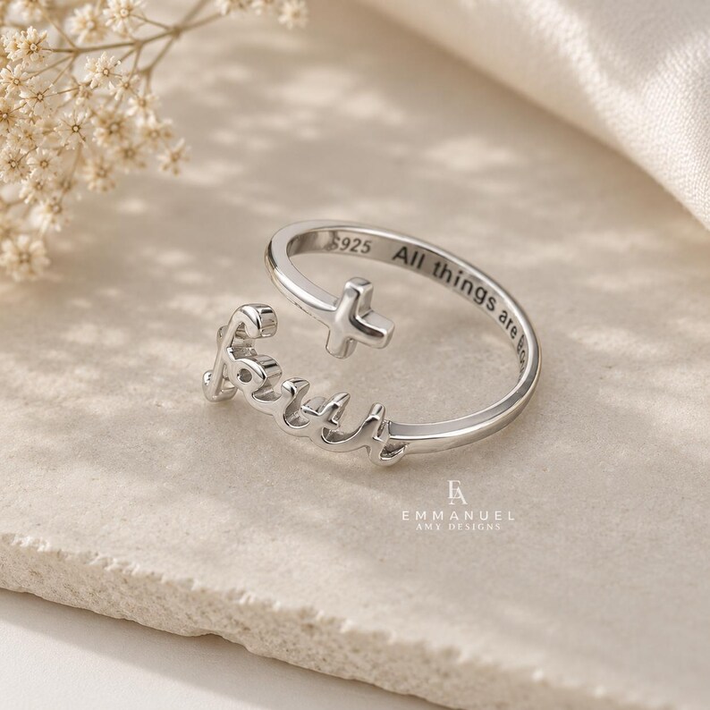 Peut inclure: Une bague ouverte de couleur argent&eacute;e pr&eacute;sentant le mot Faith en &eacute;criture cursive et un petit symbole de croix. La bande int&eacute;rieure est grav&eacute;e avec le texte S925 et All things are possible. La bague a une finition m&eacute;tallique polie et r&eacute;glable.