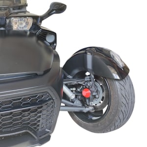 K&ouml;nnte beinhalten: Ein schwarzes dreir&auml;driges Motorrad mit Frontscheinwerfer, Seitenspiegel und gro&szlig;em Reifen. Die Vorderseite des Fahrzeugs hat einen schwarzen K&uuml;hlergrill und eine rote Komponente in der N&auml;he des Rades.