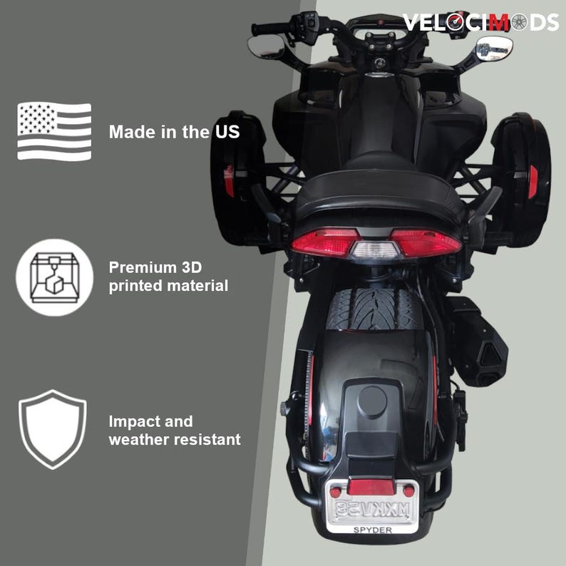 K&ouml;nnte beinhalten: Schwarzes dreir&auml;driges Motorrad mit roten R&uuml;cklichtern und seitlichen Stauf&auml;chern. Der Text "VELOCIMODS" ist sichtbar. Das Bild enth&auml;lt auch den Text "Made in the US", "Premium 3D printed material" und "Impact and weather resistant".