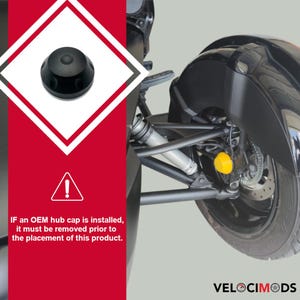 K&ouml;nnte beinhalten: Schwarze Radnabenabdeckung mit kreisf&ouml;rmigem Design, neben einem Motorradrad gezeigt. Das Bild enth&auml;lt ein Warnsymbol und den Text: "WENN eine OEM-Radnabenabdeckung installiert ist, muss sie vor der Platzierung dieses Produkts entfernt werden."