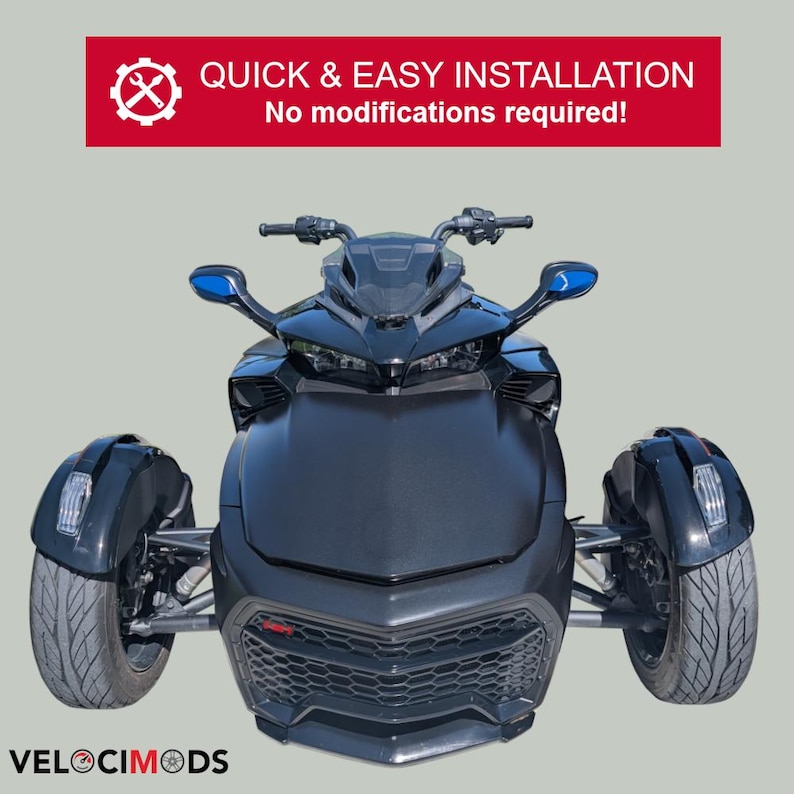 Puede incluir: Una motocicleta negra de tres ruedas con espejos laterales azules. La parte delantera del veh&iacute;culo tiene una rejilla de panal y el texto "VELOCIMODS" est&aacute; en la parte inferior. Encima de la motocicleta hay una pancarta roja con el texto "QUICK & EASY INSTALLATION" y "No modifications required!"