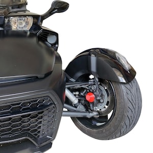 Könnte beinhalten: Ein schwarzes dreirädriges Motorrad mit matter Oberfläche. Die Front hat einen Scheinwerfer, einen Seitenspiegel und einen Wabengrill. Das Hinterrad hat einen schwarzen Kotflügel, eine Scheibenbremse und eine rote Komponente.