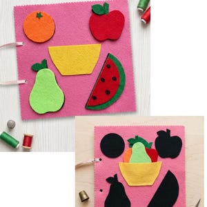 Peut inclure: Une page en feutrine rose avec des formes de fruits colorées, notamment une orange, une pomme rouge, un bol jaune, une poire verte et une tranche de pastèque. Le texte PDF Pattern | Instant Download est visible avec des bobines de fil et des dés.