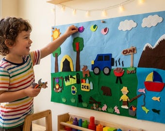 May include: A large rectangular felt board featuring a camping scene with a blue sky, white clouds, a yellow sun, green trees, a yellow tent, a blue vehicle, a brown mountain, a red boat on blue water, and various small felt shapes like fish and animals.