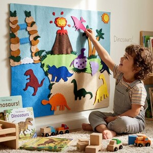 May include: A large rectangular felt board featuring a prehistoric landscape with a brown volcano, a blue waterfall, and various colorful felt dinosaur shapes including red, blue, orange, green, and yellow figures, plus a pink pterodactyl.