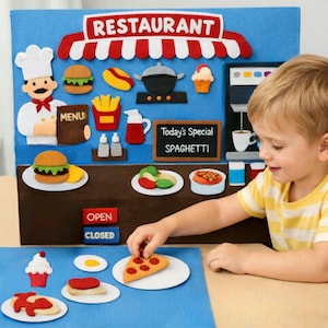 May include: A felt restaurant playset with a blue background and a red and white striped awning. The set includes felt food items like burgers, fries, and pizza. A child is interacting with the playset, adding a pizza slice to a plate.