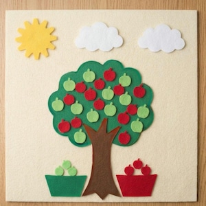 May include: A square cream-colored felt board featuring a brown tree trunk with a large green canopy. The tree is decorated with red and light green felt apples. Above the tree are a yellow sun and two white clouds. Two baskets hold apples.