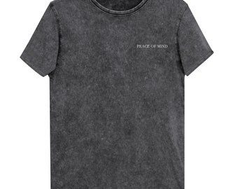 Könnte beinhalten: Dunkelgraues T-Shirt mit dem weißen Schriftzug "PEACE OF MIND". Das Shirt hat einen Rundhalsausschnitt und kurze Ärmel. Der Stoff hat ein strukturiertes, leicht verwaschenes Aussehen.