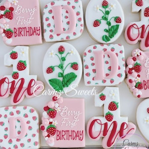 Op de afbeelding: Een set van negen gedecoreerde suikerkoekjes met een aardbeien thema. De koekjes bevatten het nummer &eacute;&eacute;n, de letter D en de woorden "Berry First Birthday".