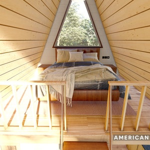 May include: A wooden loft bed with a wooden railing and a window above the bed. The bed is made with a blue and white patterned blanket and a brown throw blanket. The room is lined with wood paneling.