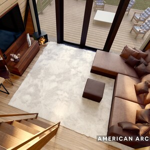 May include: A top-down view of a living room with a large sectional sofa, a white rug, a coffee table, and a television mounted on the wall. The room has a wooden floor and a wooden staircase leading up to the next level. The text "AMERICAN ARCHITECTS" is visible in the bottom right corner of the image.