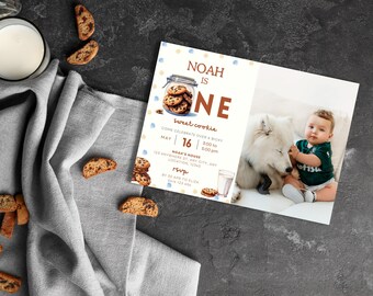Può includere: Un invito illustrato blu e marrone per un primo compleanno. L'invito presenta un barattolo di biscotti con biscotti e il testo "Noah ha un anno, un biscotto dolce". L'invito include anche la data, l'ora e il luogo della festa. Una foto di un bambino con un cane bianco è sullo sfondo.