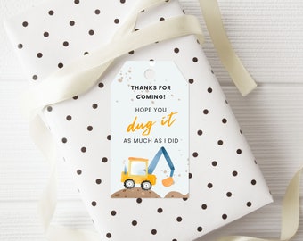 May include: A yellow construction vehicle with a blue arm and a scoop. The vehicle is on a brown dirt mound. The text on the tag reads "Thanks for coming! Hope you dug it as much as I did."