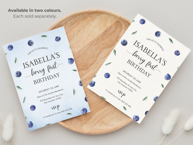 May include: Two printable invitations for a first birthday party. The invitations feature a watercolor design with blueberries and leaves. The text on the invitations reads "Join us to celebrate Isabella's berry first birthday" and includes the date, time, and location of the party. The invitations also include the text "RSVP" and contact information.