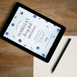 May include: A digital invitation on a tablet screen for Isabella's first birthday party. The invitation features a watercolor design with blueberries and leaves on a light blue background. The text reads "Join us to celebrate Isabella's berry first birthday. Saturday 22 June. 12pm of the Jacobs Residence. 123 Anywhere St. Any City. Any Location 12545. RSVP to Amelis by 5 June, 0141125 456."