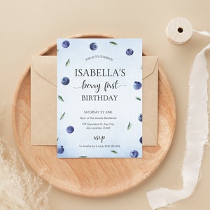 May include: A blue and white birthday invitation with watercolor blueberries and green leaves. The invitation reads "Join us to celebrate Isabella's berry first birthday. Saturday 22 June 12pm at the Jacobs Residence 125 Anywhere St, Any City, Any Location 12545 rsvp To Amelia by 5 June, 0141125 456"