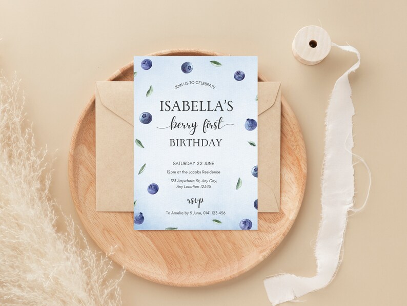 May include: A blue and white birthday invitation with watercolor blueberries and green leaves. The invitation reads "Join us to celebrate Isabella's berry first birthday. Saturday 22 June 12pm at the Jacobs Residence 125 Anywhere St, Any City, Any Location 12545 rsvp To Amelia by 5 June, 0141125 456"