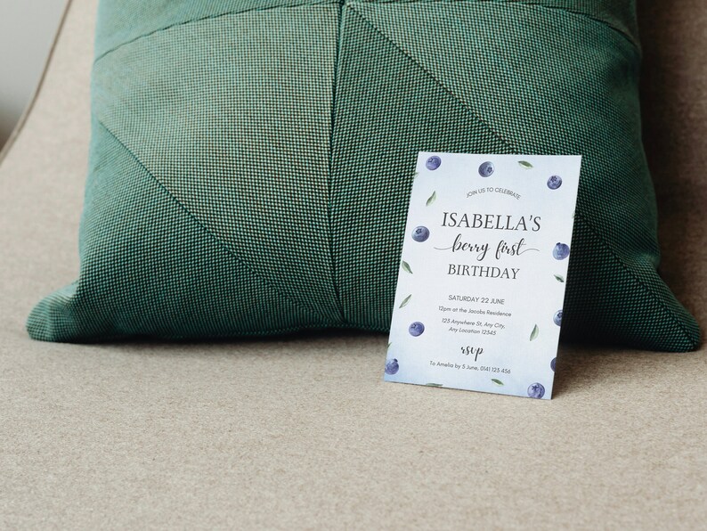 May include: A blue and white birthday invitation with a watercolor blueberry design. The invitation reads "Join us to celebrate Isabella's berry first birthday. Saturday 22 June 12pm at the Isabelle Residence 123 Anywhere St, Any City, Any Location 12345 RSVP To Amelia by 5 June, 0123 123 456".