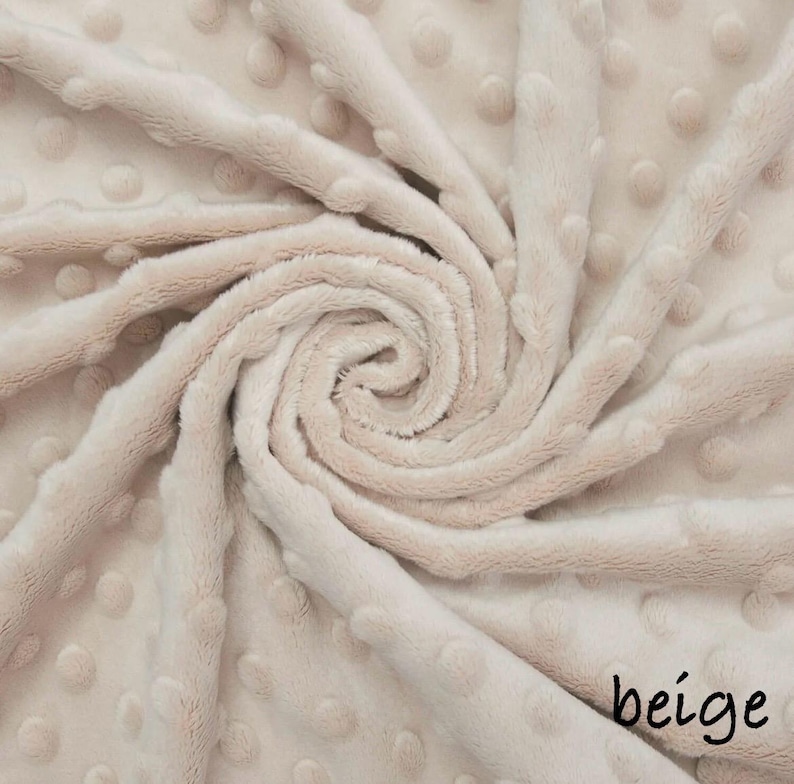 May include: Beige plush fabric with a textured, dotted pattern. The fabric is arranged in a spiral, with the word "beige" in a handwritten font in the bottom right corner. The material appears soft and inviting.